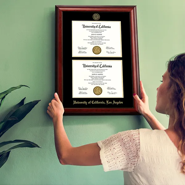 Person hanging a double diploma frame