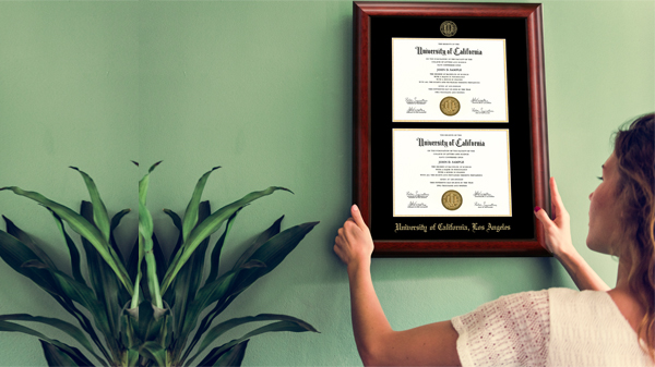 Girl Hanging Her University of California, Los Angeles Double Diploma Frame on Wall